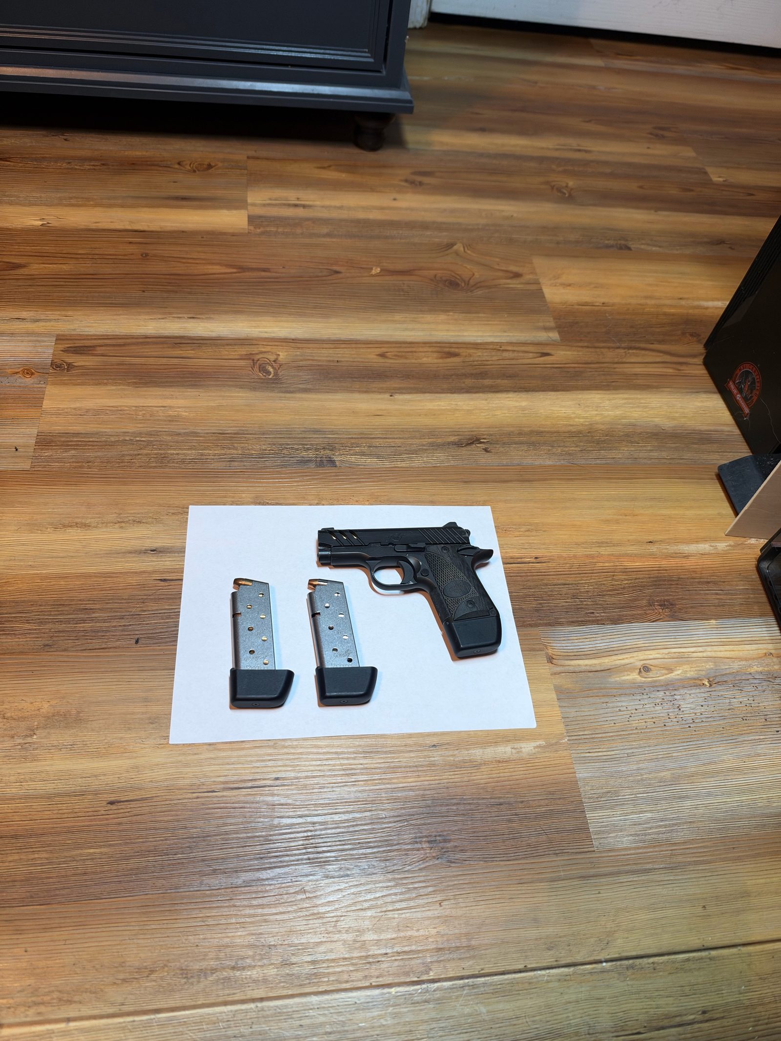 A gun and magazines on printer paper, shot from too far away so the sheet is small in the frame.