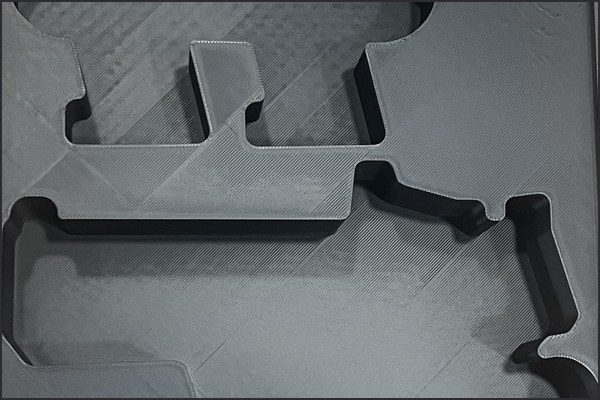 Close-up of a gray 3D-printed insert with a pistol pocket.
